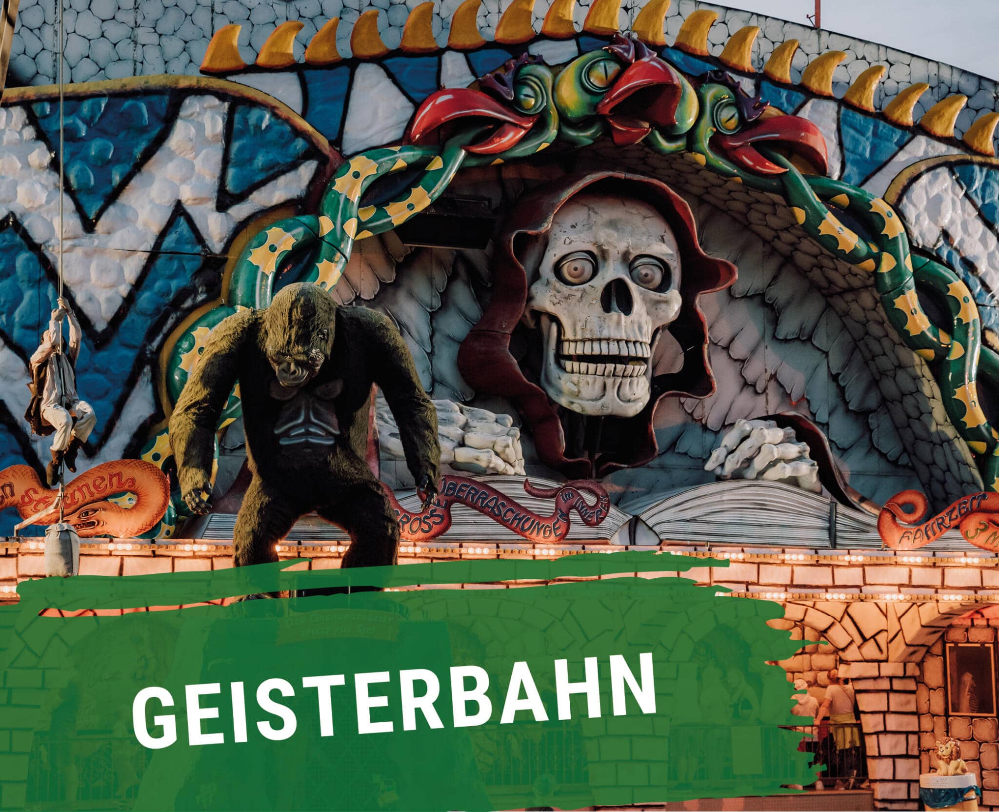 Geisterbahn-Fassade mit bunten Grusel-Figuren: riesiger Totenkopf, Gorilla-Figur und Schlangen-Dekorationen
