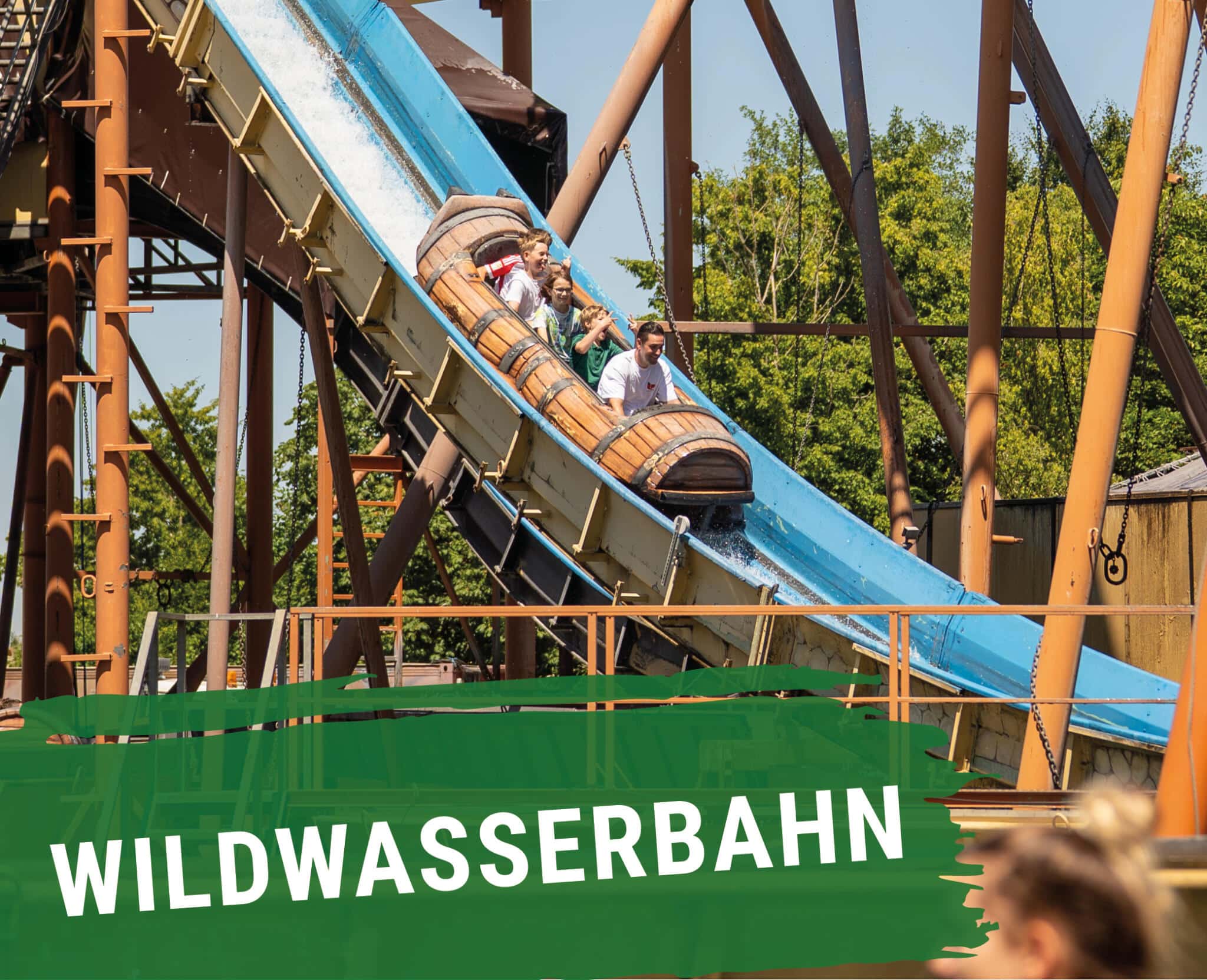 Wildwasserbahn: Besucher fahren in einem fassförmigen Boot eine steile Wasserrutsche hinunter