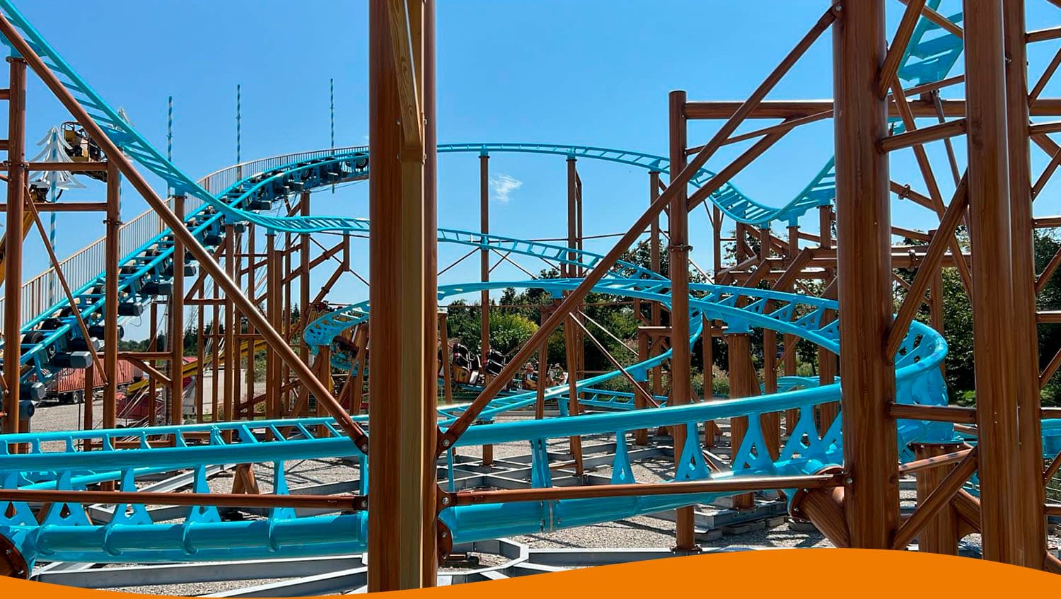 Achterbahn mit blauen Schienen und Holzstruktur in einem Freizeitpark unter blauem Himmel.
