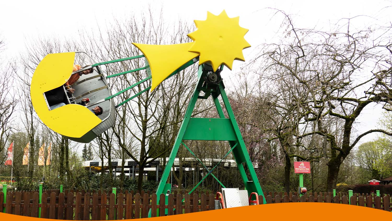 Komet Fahrgeschäft mit gelbem Sonnen-Design und Fahrgästen in einem Freizeitpark.