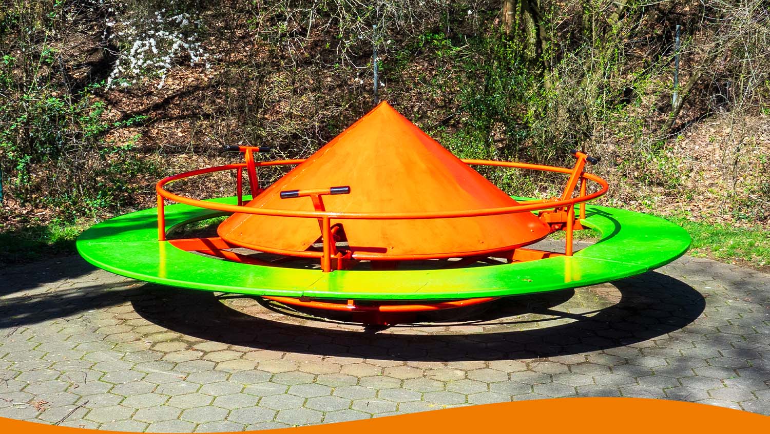 Bunte Drehscheibe in orange und grün auf einem Spielplatz mit runder Plattform.