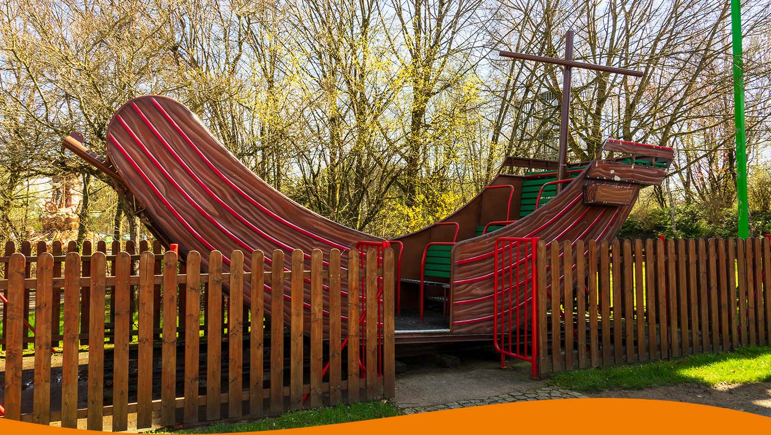 Ein Spielgerät in Form eines Schiffes auf einem Kinderspielplatz mit Holzumrandung.