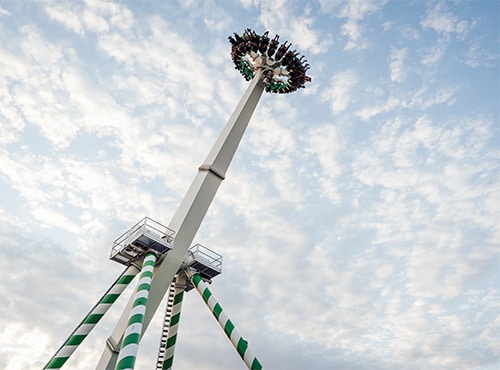 Sky-Wheel Fahrgeschäft mit Fahrgästen in großer Höhe unter einem bewölkten Himmel.