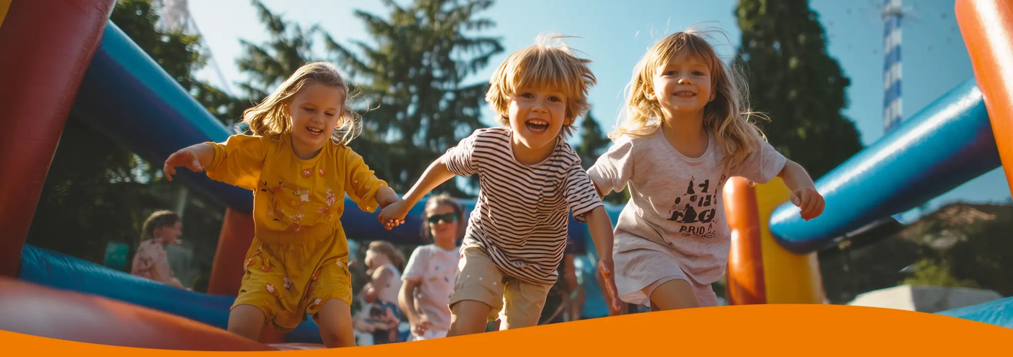 Drei Kinder, die fröhlich auf einer Hüpfburg spielen und lachen.