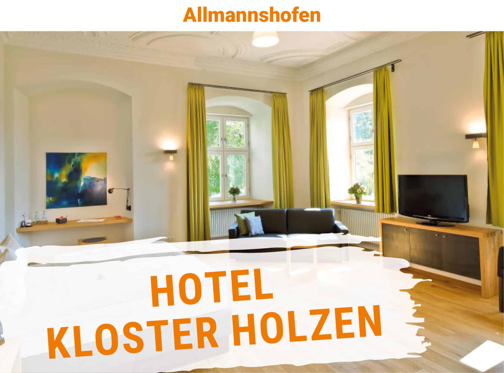 Heller Hotel-Zimmer Innenraum im Hotel Kloster Holzen mit großen Fenstern, grünen Vorhängen, schwarzem Sofa und einer Holz-TV-Mediapräsentschrank, natürliche Lichtstimmung