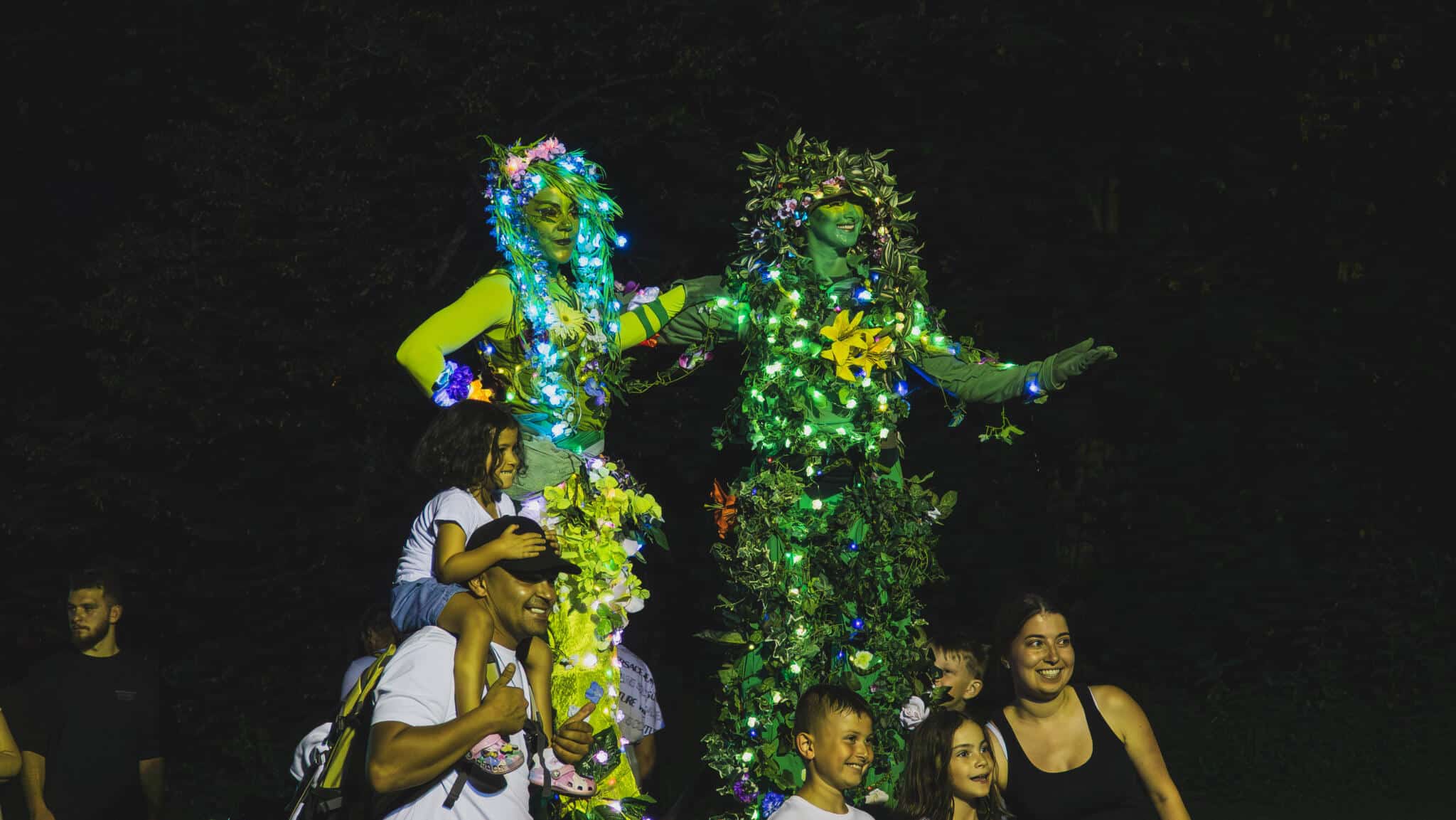 Stelzenläufer in Blätter Outfit an Skyline Park bei Nacht