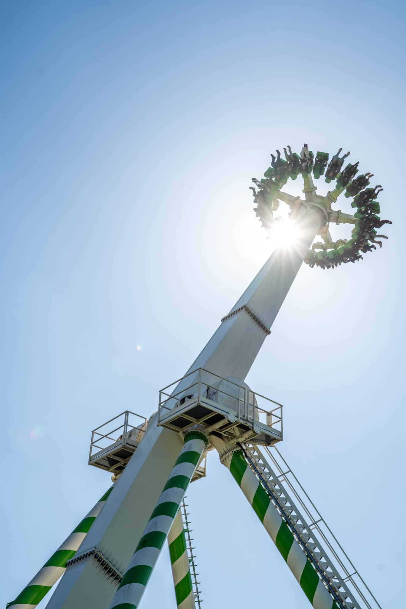 Sky-Wheel Fahrgeschäft mit Fahrgästen in großer Höhe unter einem sonnigen Himmel.