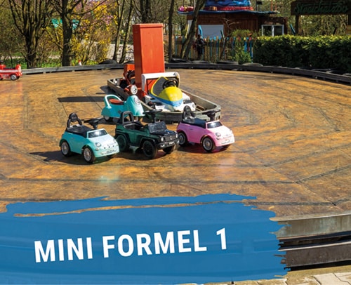 Mini Formel 1 Autos in verschiedenen Farben auf einer runden Fahrbahn angeordnet.