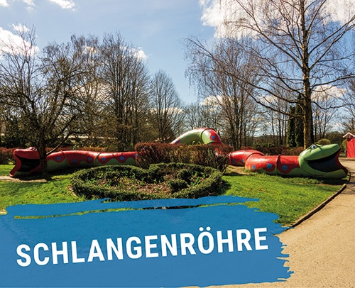 Bunte Schlangenröhre mit grünen und roten Elementen im Freizeitpark.