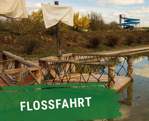 Holzfloss mit weißen Segeln auf einem Gewässer im Skyline Park.