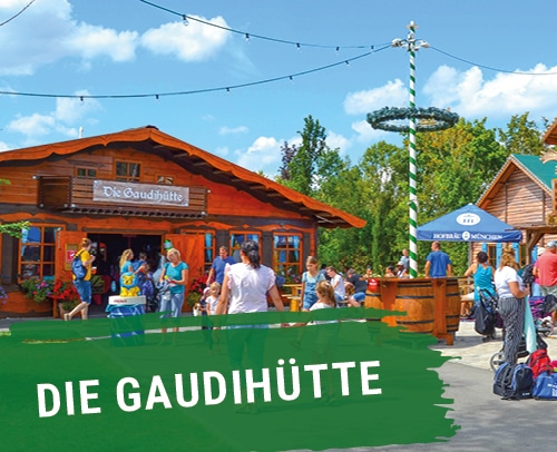 Holzhütte mit dem Namen 'Die Gaudihütte' und Menschen in der Umgebung im Skyline Park.