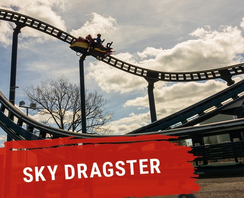 Achterbahnfahrzeug auf der Sky Dragster Strecke mit Fahrgästen in der Luft.