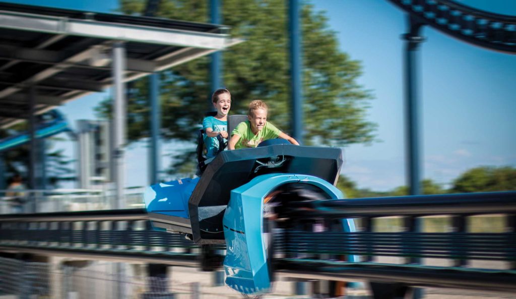 Zwei Kinder fahren auf der SkyDragster Achterbahn in einem Freizeitpark.